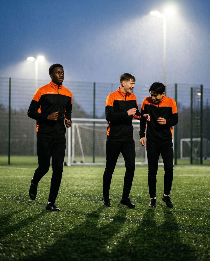 Spieler in schwarz-orangen Stanno-Pride-Trainingsjacken